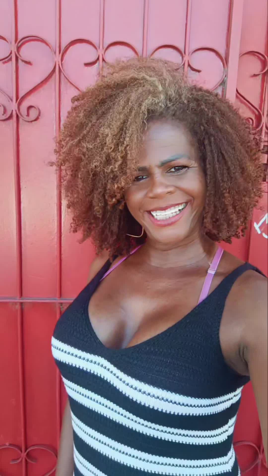 Mulher negra charmosa com cabelos cacheados e top preto
