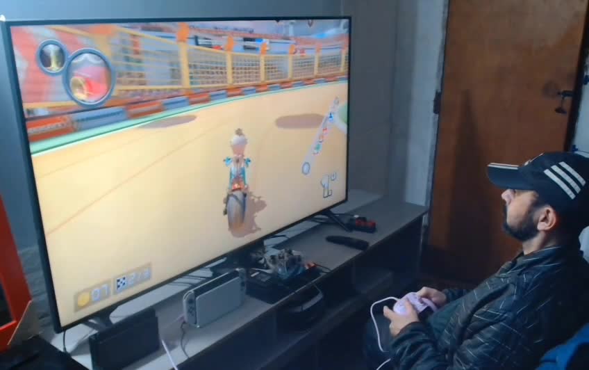 Homem com boné jogando videogame em tela grande