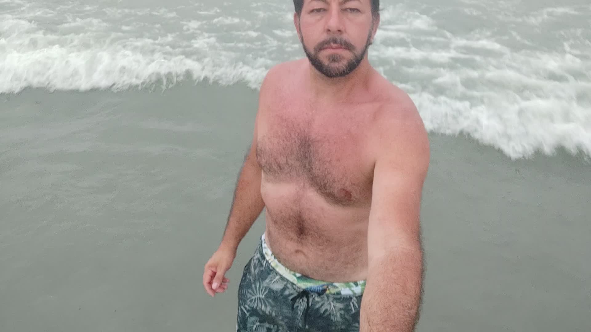 Homem barbudo com corpo bronzeado e molhado na praia