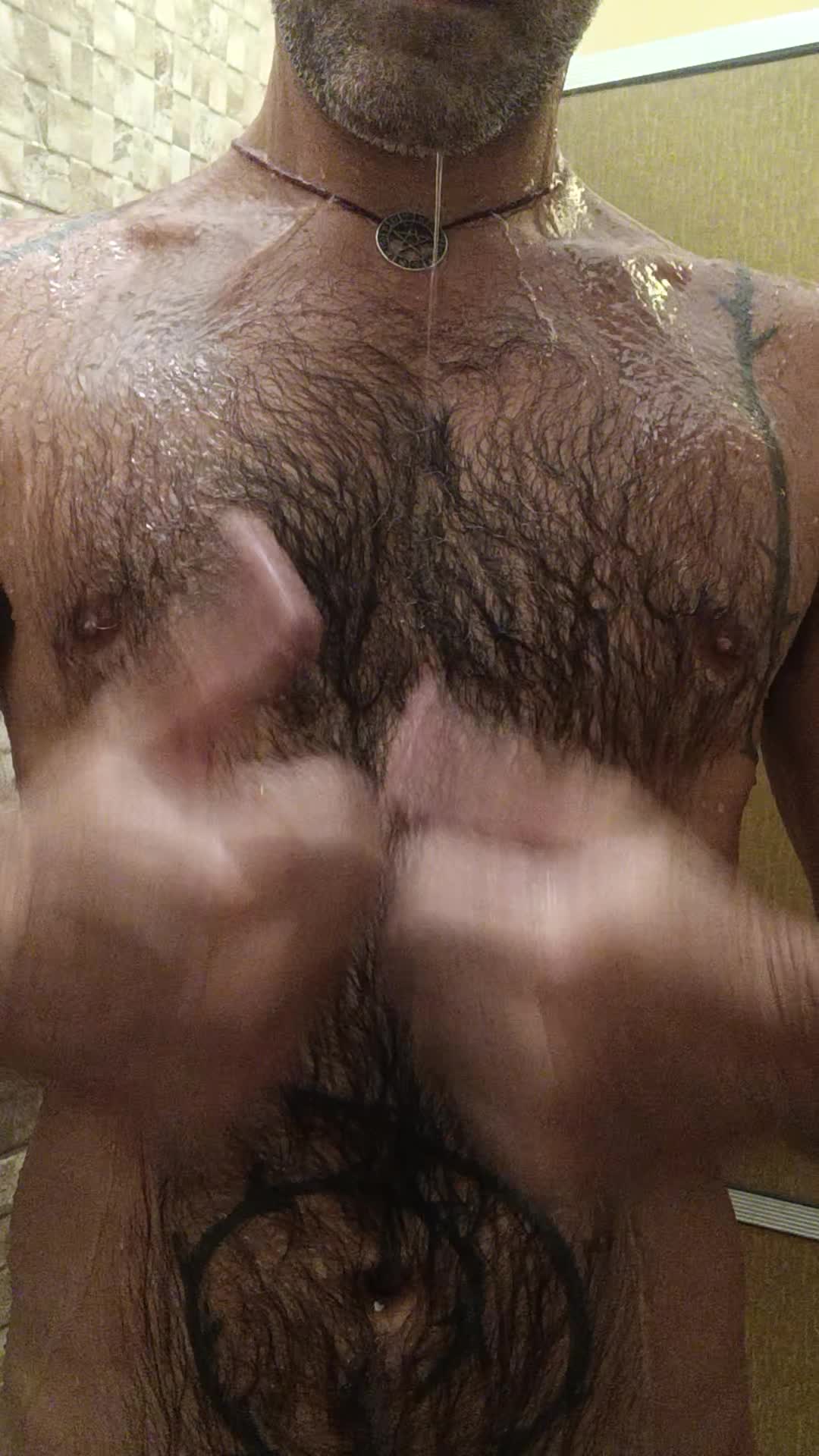 Homem sensual no chuveiro com close no corpo molhado