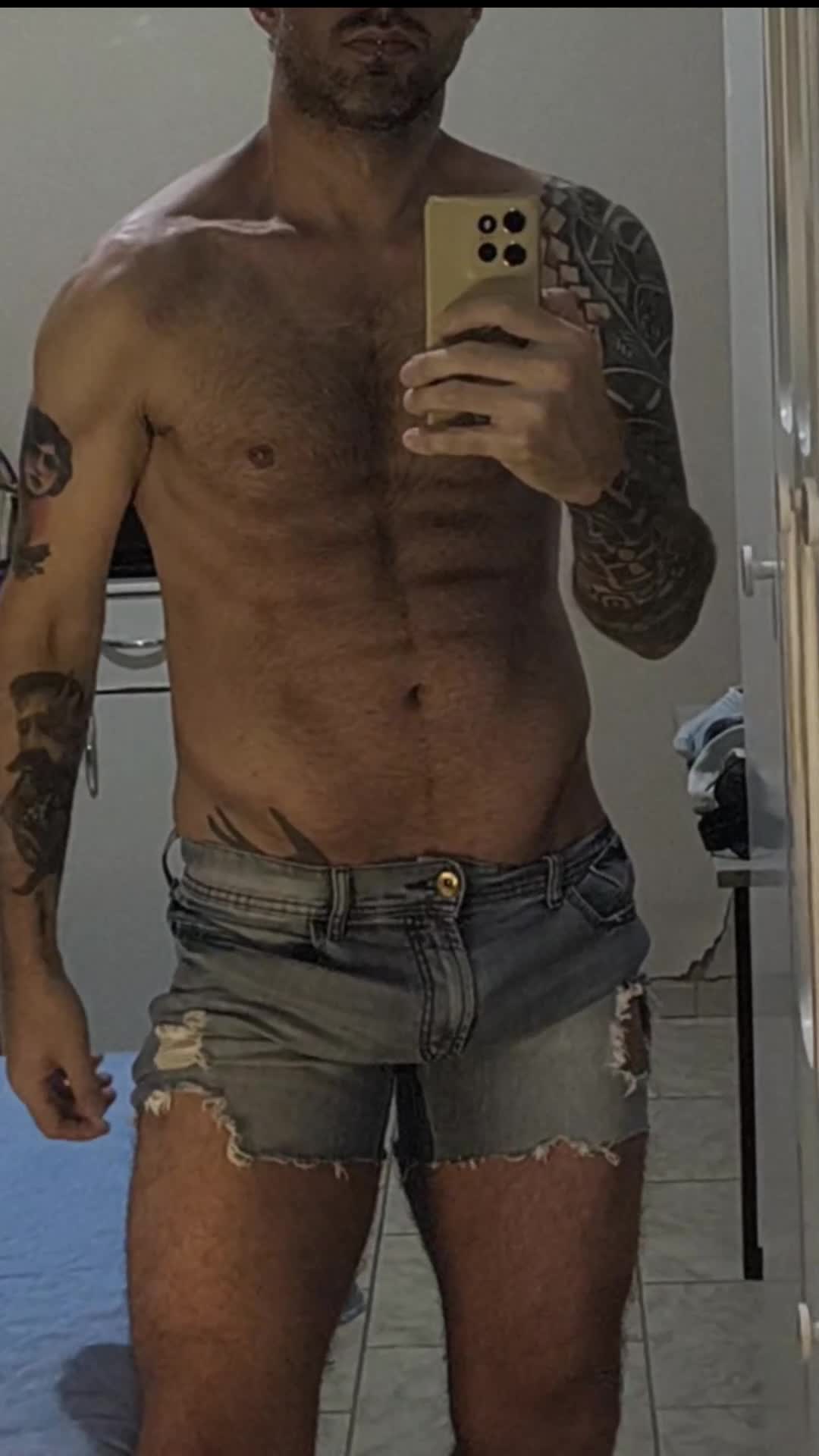Gostoso de shorts jeans e tatuagens provocantes