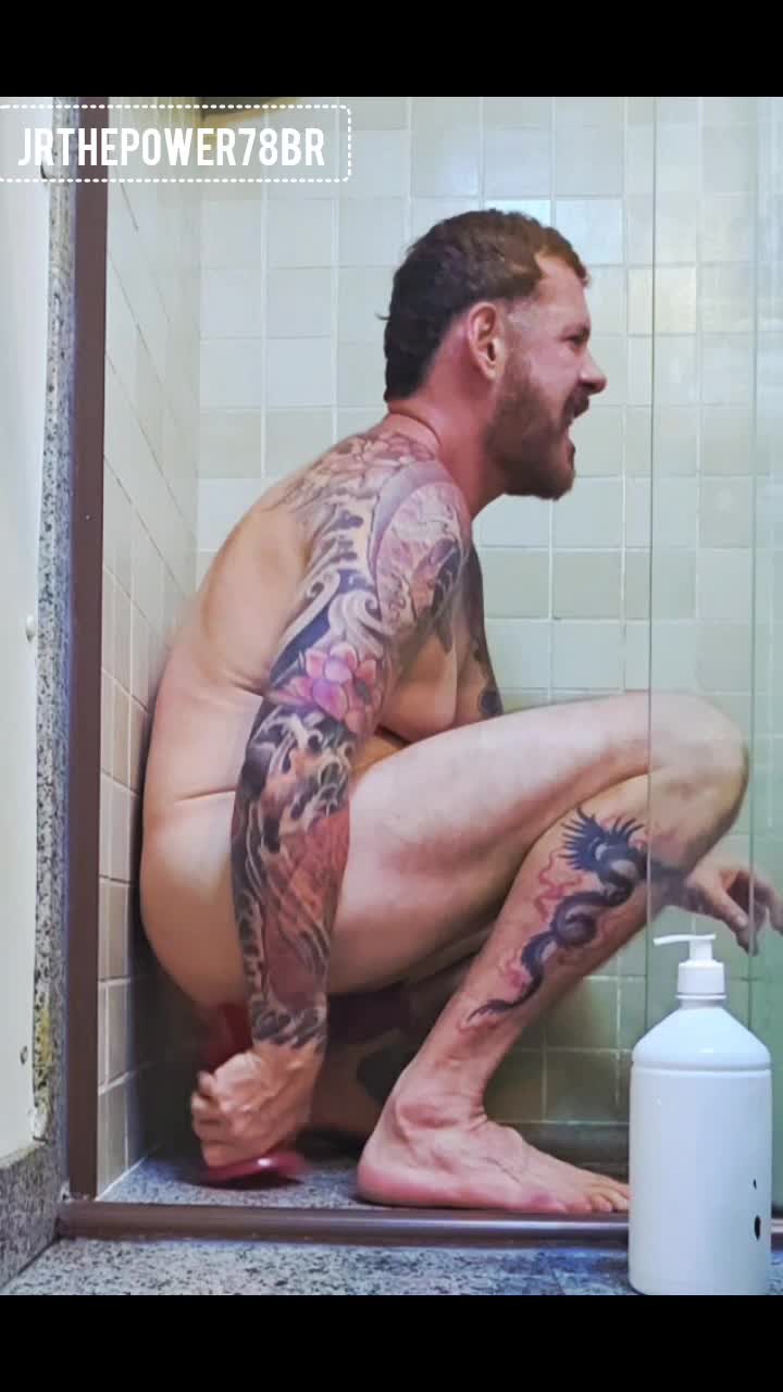 Homem tatuado explorando masturbação e prazer anal no chuveiro